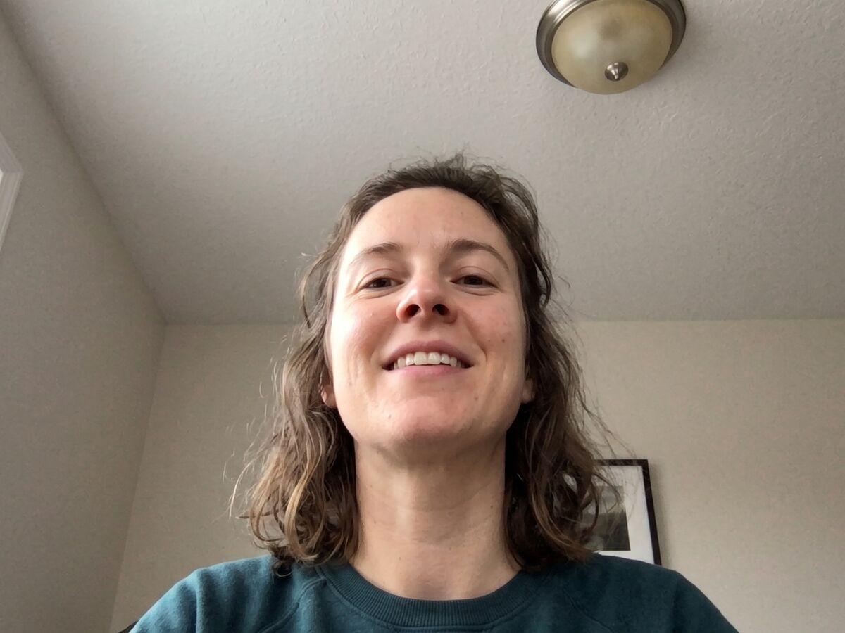 A woman seen from below by a laptop camera. The view shows under her chin and the ceiling light.